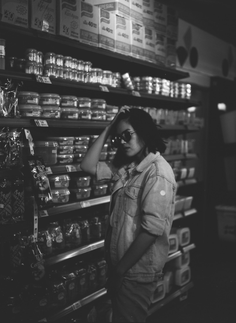 Black and white film photo of Filananda in a supermarket aisle